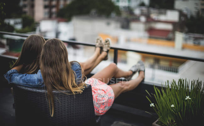 Молодые женщины сидят на крыше — стоковое фото