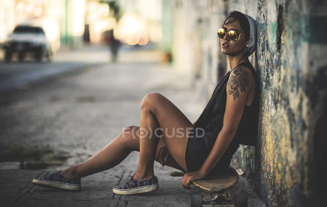 Женщина сидит на скейтборде — стоковое фото
