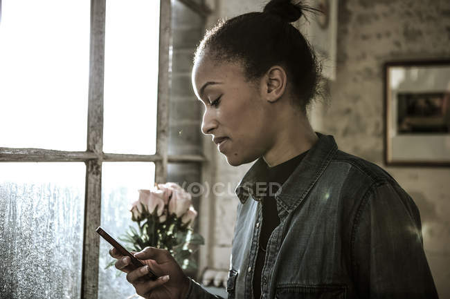 Young woman standing by window — Stock Photo