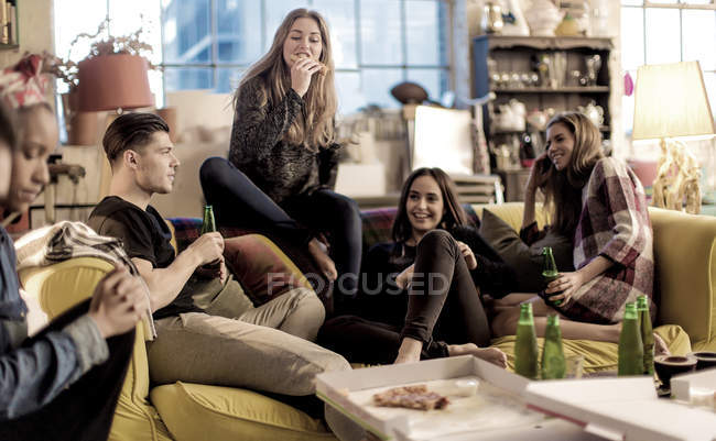 Mujeres y hombres jóvenes en el sofá, sonriendo - foto de stock