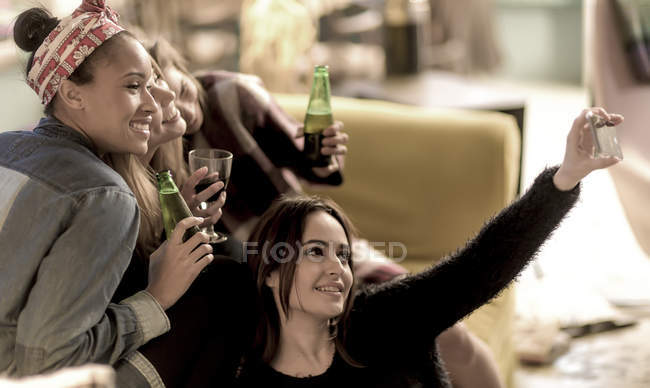 Молоді жінки, сидячи на дивані, сміються — стокове фото