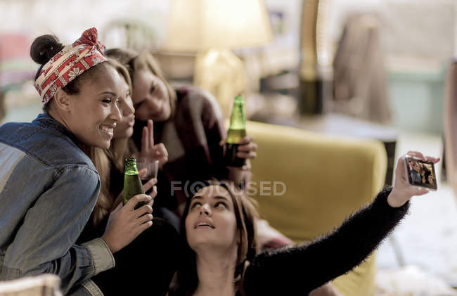 Молоді жінки, сидячи на дивані, сміються — стокове фото