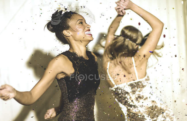 Mujeres jóvenes bailando con confeti cayendo . - foto de stock