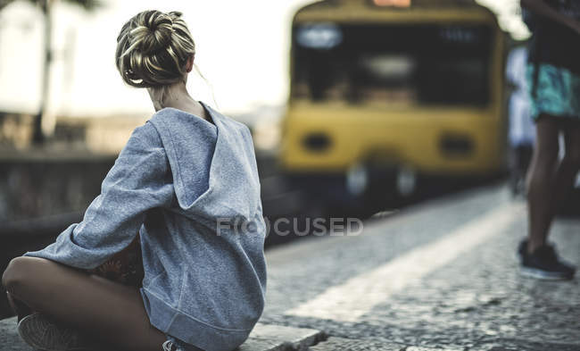 Donna seduta sulla piattaforma della stazione ferroviaria — Foto stock
