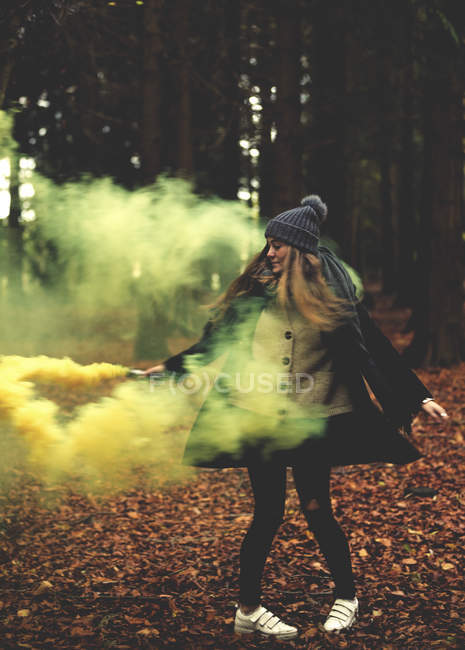 Жінка махає жовтим димом в лісі . — стокове фото