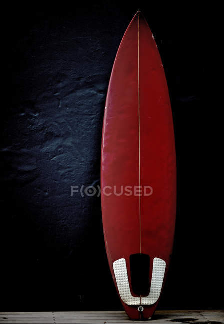 Tabla de surf roja apoyada en la pared . - foto de stock