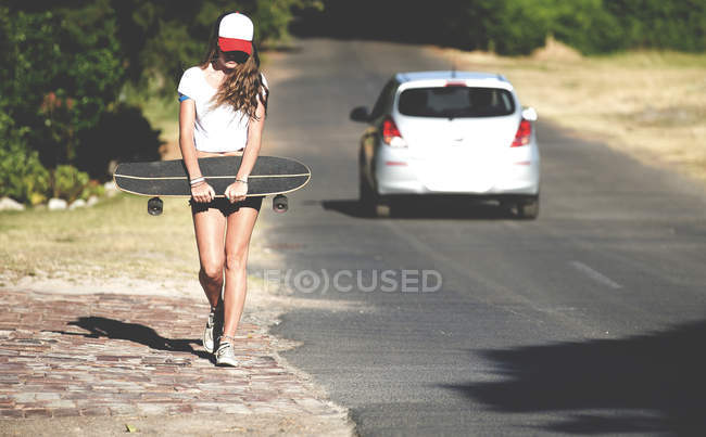 Young woman walking beside road — Stock Photo