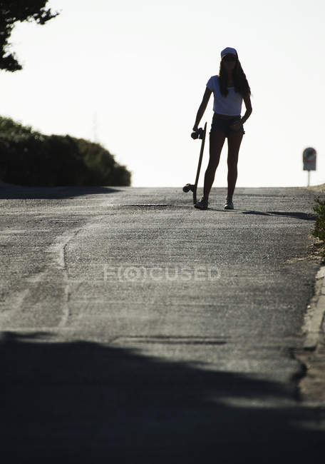 Young woman standing with skateboard. — Stock Photo