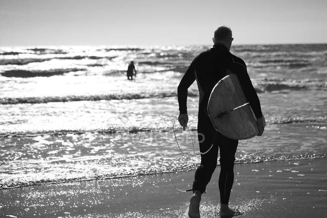 Uomo che trasporta tavola da surf . — Foto stock