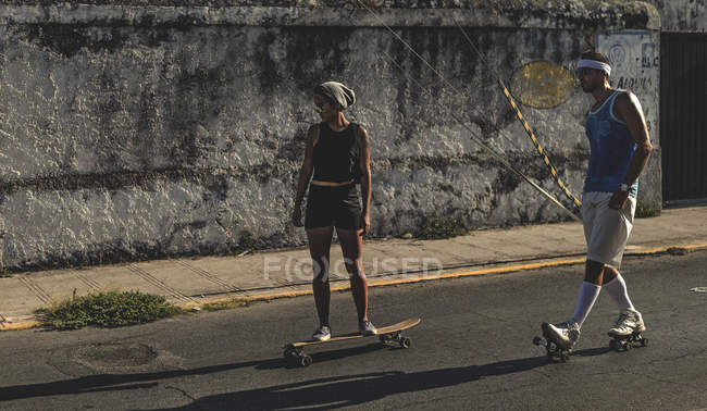 Frau und Mann Skateboarden und Rollschuhlaufen — Stockfoto