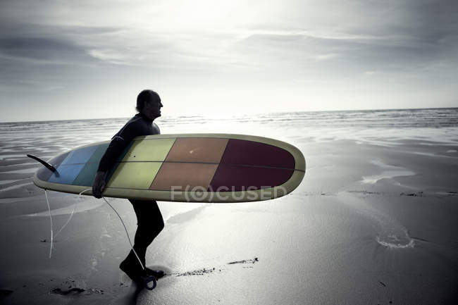 Uomo che trasporta tavola da surf . — Foto stock
