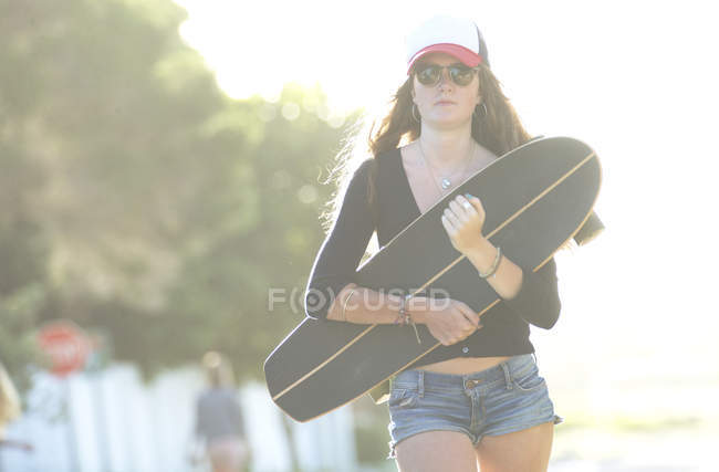 Junge Frau trägt Skateboard — Stockfoto
