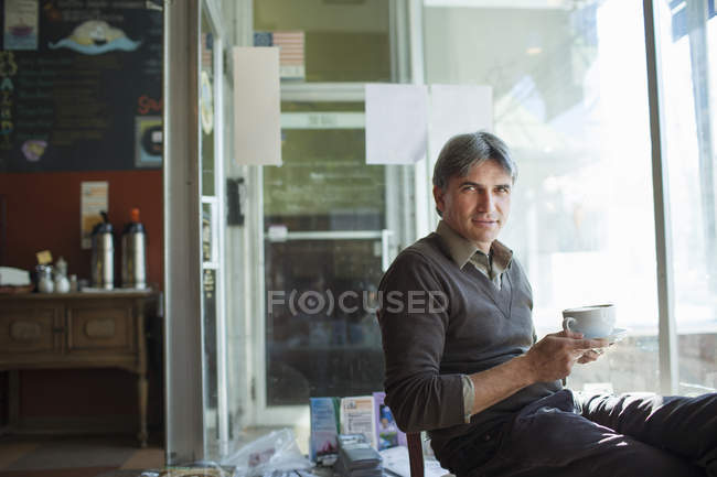 Maduro homem sentado no café com copo — Fotografia de Stock