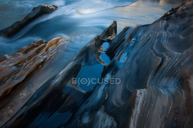 Textured rock at edge of stream — Stock Photo