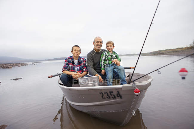 Mature man and boys sitting in fishing boat at Ashokan Reservoir — Stock Photo