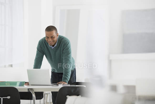 Homem de pé na mesa e usando um laptop no escritório — Fotografia de Stock