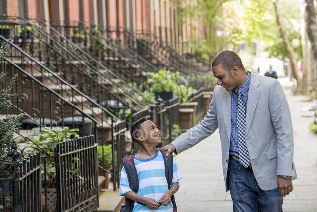 Father and son looking at each other while walking together on street in city. — Stock Photo