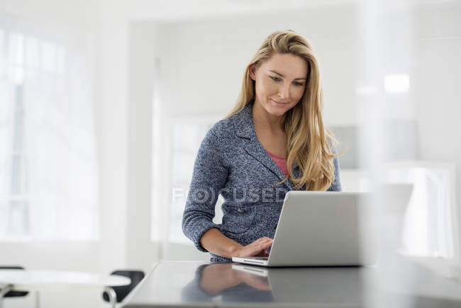 Женщина сидит за столом с ноутбуком — стоковое фото