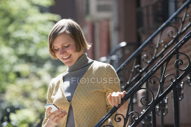 Woman checking smartphone on building steps — Stock Photo