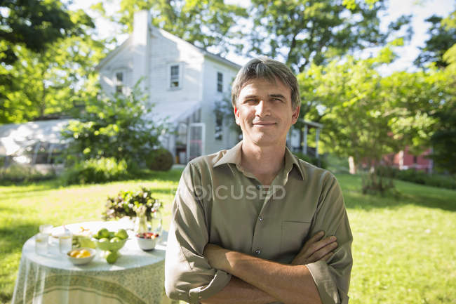 Чоловік стоїть в саду ферми біля столу зі свіжим лимонадом — стокове фото