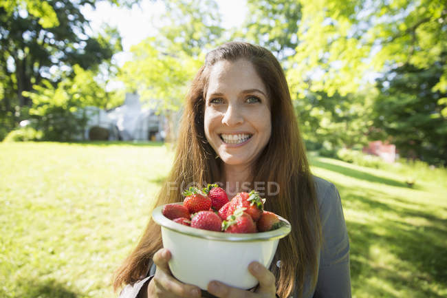 Femme portant un bol de fraises fraîches cueillies biologiques . — Photo de stock