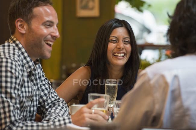 Amigos sentados alrededor de la mesa en la cafetería y tomando bebidas . - foto de stock