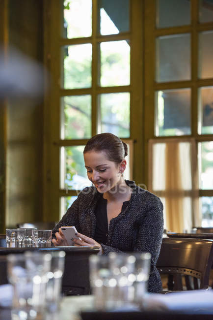 Frau checkt Telefon am Tisch in Restaurant — Stockfoto