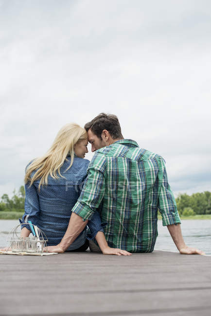 Uomo e donna seduti vicini sul molo del lago — Foto stock