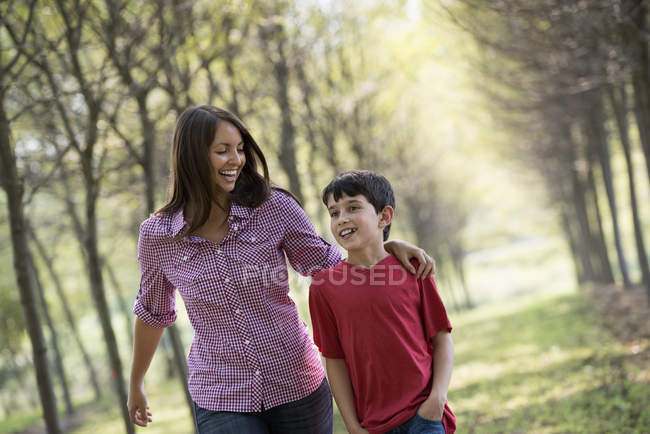 Woman and child walking down avenue of trees. — Stock Photo