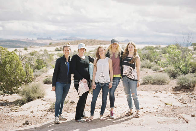 Groupe de cinq amies souriantes debout dans un paysage désertique — Photo de stock