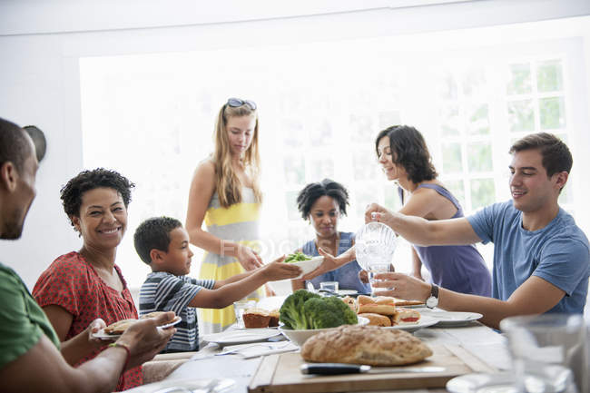 Família de homens, mulheres e crianças compartilhando refeição na mesa de jantar . — Fotografia de Stock