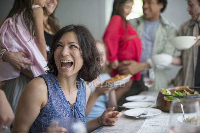 Frau lacht beim Abendessen mit Erwachsenen und Kindern am Tisch. — Stockfoto