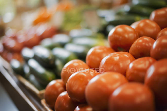 Farm stand display of fresh tomatoes and cucumbers. — Stock Photo