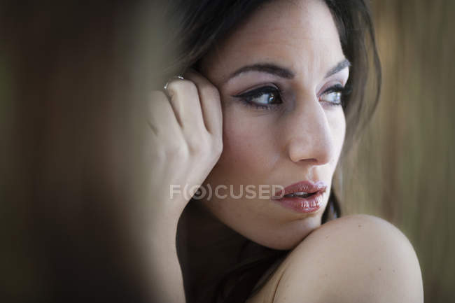 Woman with makeup looking away with hand by face, portrait. — Stock Photo