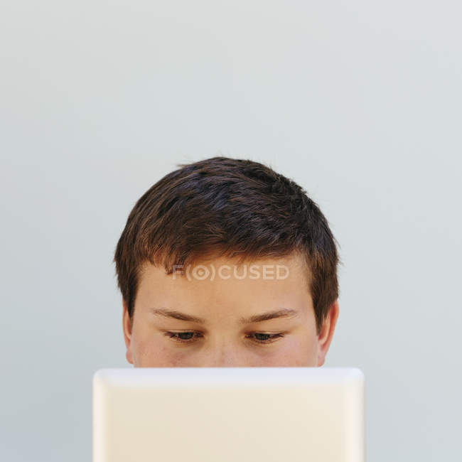 Portrait d'un adolescent tenant une tablette numérique couvrant la moitié du visage . — Photo de stock