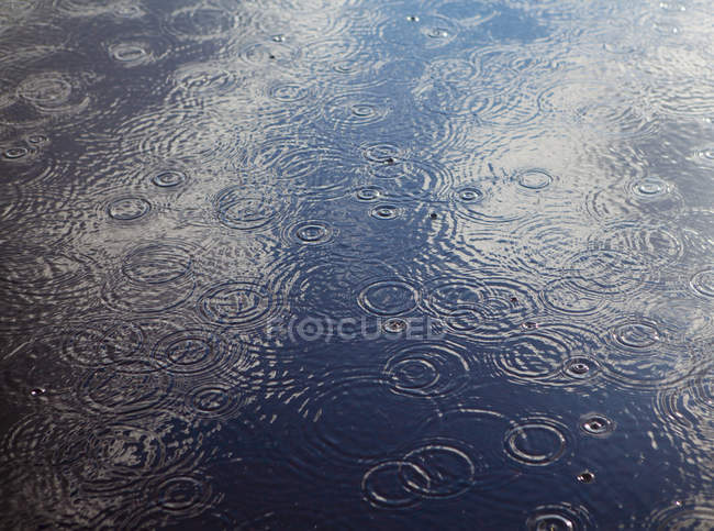 Regentropfen und Wellen auf Wasserbecken. — Stockfoto