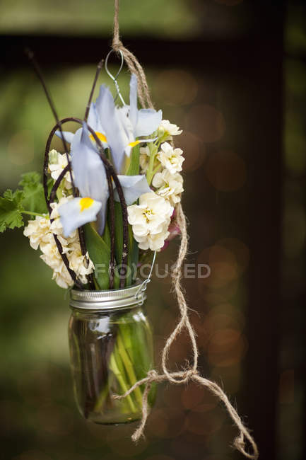 Frasco de vidro pendurado de arame com íris e flores brancas perfumadas . — Fotografia de Stock