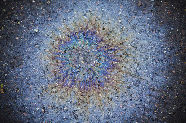 Olio versato modello irradiante con effetto multicolore su strada . — Foto stock
