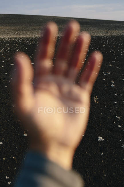 Male hand in foreground of solidified lava field. — Stock Photo
