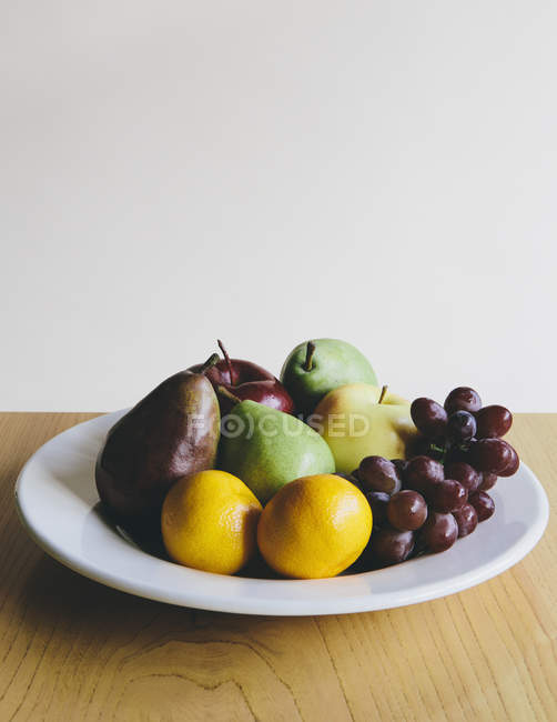 Plate of organic fresh tangerines, grapes, pears and apples — Stock Photo