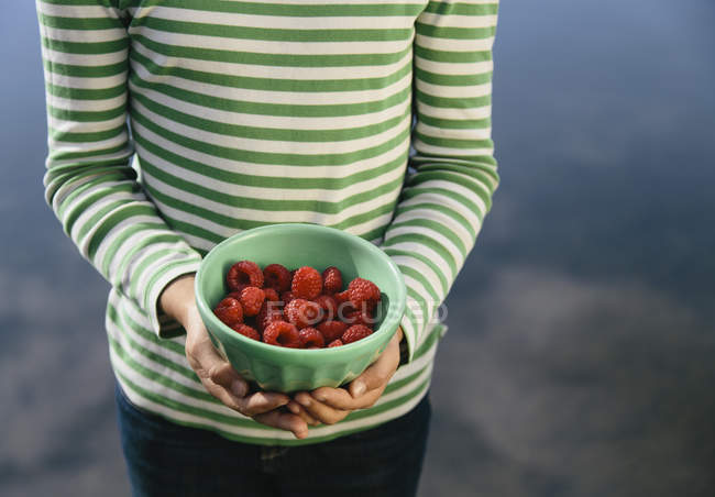 Cropped view of girl holding bowl of organic raspberries — Stock Photo