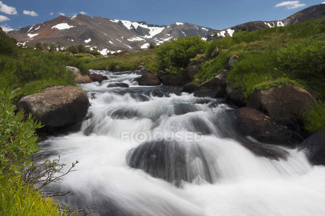 Cascade of fast flowing white water over rocks in valley in mountains. — Stock Photo
