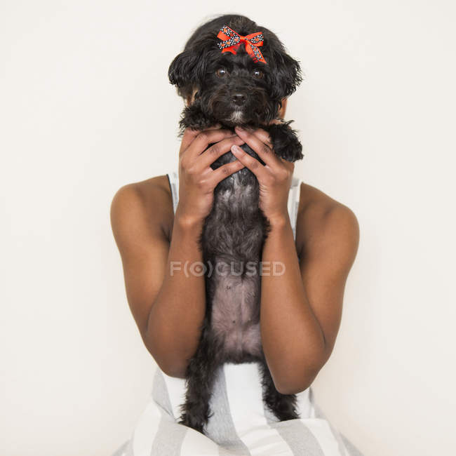Teenage girl holding small black pet dog in hands. — Stock Photo
