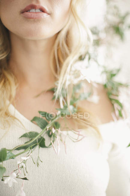 Обрізаний вид блондинки посміхається з квітковою гірляндою навколо плечей . — стокове фото