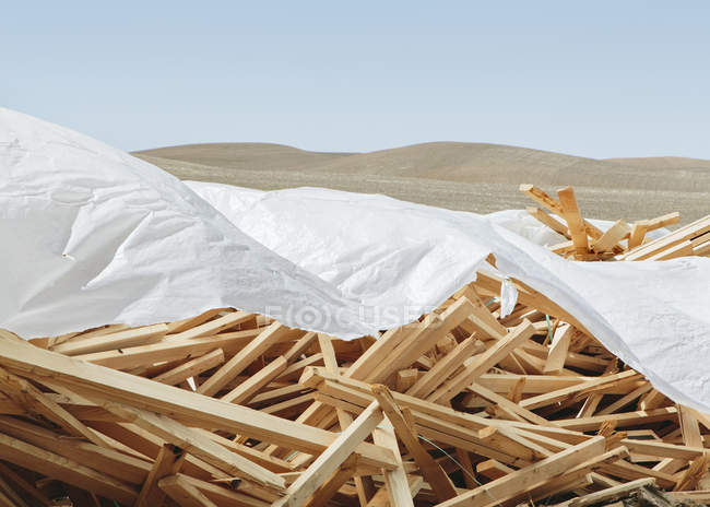 Weiße Plane bedeckt Haufen von Holzbolzen für den Bau verwendet. — Stockfoto