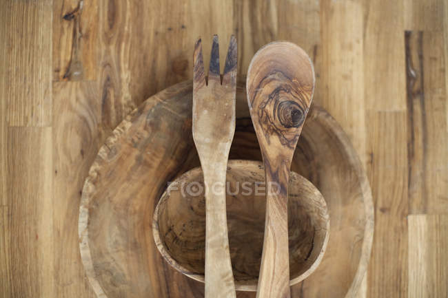 Wooden tabletop with bowls and wooden salad servers. — Stock Photo