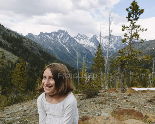 Ragazza pre-adolescente seduta di vedetta con le montagne della foresta nazionale di Wenatchee, Washington, USA . — Foto stock