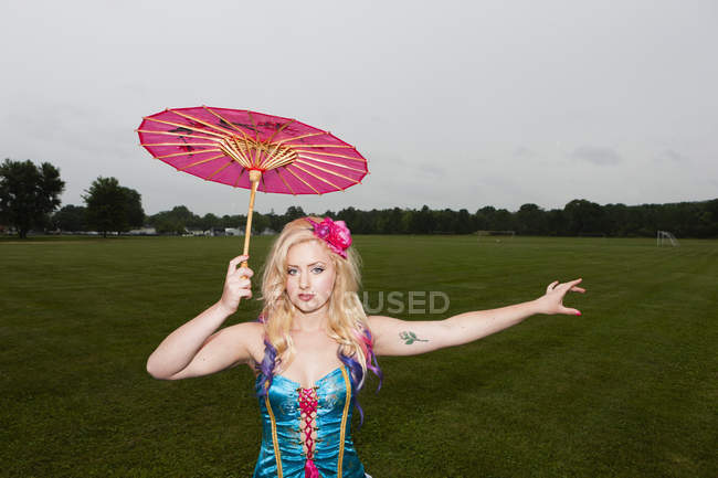 Young woman in laced basque holding paper sunshade umbrella. — Stock Photo