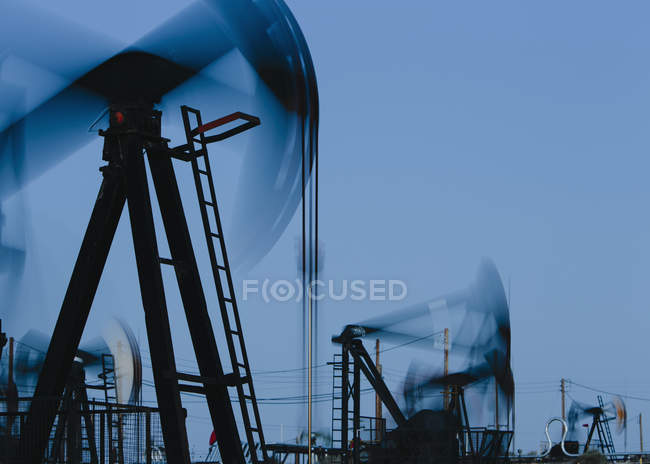 Funktionierende Ölindustrie pumpt in der Mitte des Sonnenuntergangs Ölfeld in Kalifornien, Vereinigte Staaten — Stockfoto