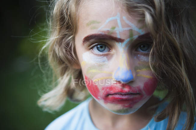 Elémentaire fille d'âge avec visage décoré avec des peintures
. — Photo de stock